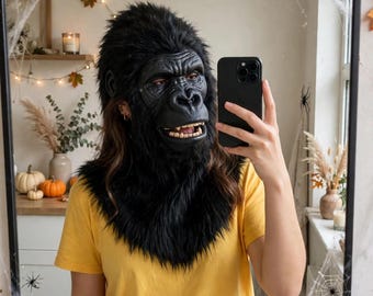 Puede incluir: Una máscara de gorila realista con piel sintética negra, un rostro negro moldeado con rasgos detallados y dientes visibles. La máscara cubre la cabeza y el cuello, combinada con una camiseta amarilla lisa de manga corta que lleva la persona.