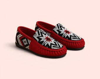 Può includere: Un paio di scarpe rosse in stile mocassino con intricate perline. Le tomaie presentano un design geometrico in nero, bianco e rosso. Le scarpe hanno una consistenza morbida, simile alla pelle scamosciata, e un classico design slip-on.