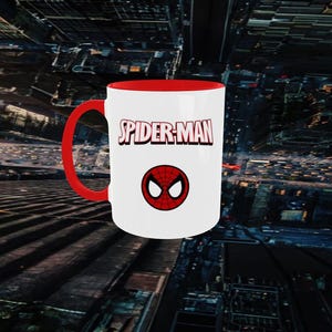 May include: A white ceramic mug with a red interior and handle. The mug features the text "SPIDER-MAN" in red and a red and black spider symbol. The mug is a standard size for coffee or tea.