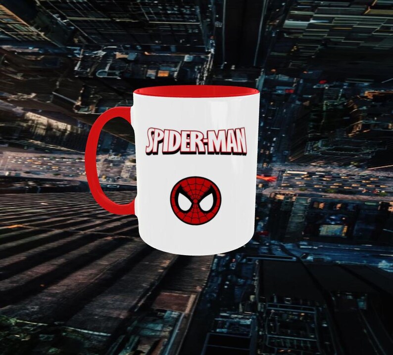 May include: A white ceramic mug with a red interior and handle. The mug features the text "SPIDER-MAN" in red and a red and black spider symbol. The mug is a standard size for coffee or tea.