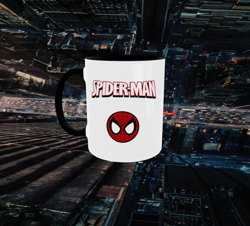 May include: White ceramic mug with a black handle and interior. The mug features the words "SPIDER-MAN" in red and white, along with a red and black spider symbol. The mug is a fan item.
