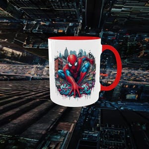 May include: White ceramic mug with a red interior and handle. The mug features a colorful illustration of Spider-Man in a city setting. The superhero is depicted in his iconic red and blue suit.