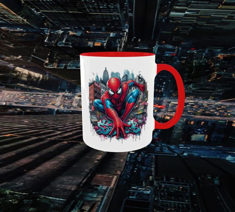 May include: White ceramic mug with a red interior and handle. The mug features a colorful illustration of Spider-Man in a city setting. The superhero is depicted in his iconic red and blue suit.