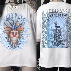 May include: White t-shirt featuring a colorful illustration of a deer-like creature with a tree-like head and a blue and orange background. The back of the shirt has the text "PRINCESS MONONOKE" above a graphic of a deer and a waterfall.