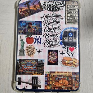 Könnte beinhalten: Eine rechteckige Tablethülle mit einer Collage aus New York City-Motiven, darunter die Freiheitsstatue, eine U-Bahn, die Brooklyn Bridge, eine Bodega-Katze sowie Schriftzüge wie New York City, Manhattan, Brooklyn, Queens, Bronx, Staten Island und I Love NY.
