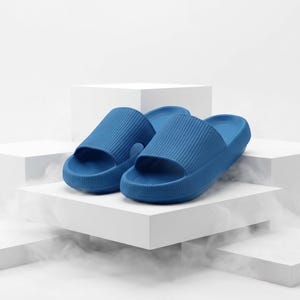 May include: A pair of bright blue slip-on sandals featuring a thick, textured sole and a wide, ribbed upper strap. The footwear has a rounded toe design and a contoured footbed, constructed from a solid, uniform material with a matte finish.