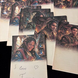 Op de afbeelding: Een verzameling rechthoekige briefpapierbladen met fantasy-illustraties van elfachtige figuren die schrijven in een bibliotheek. Het onderste vel bevat de handgeschreven tekst "I love Faerwyn" met een hartsymbool in zwarte inkt.