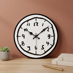 Peut inclure: Une horloge murale ronde avec un cadran blanc et des chiffres noirs dessinés à la main, ainsi qu'une bordure noire. Les aiguilles sont noires et la trotteuse est rouge. L'horloge est posée sur une surface en bois.