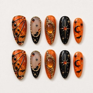 May include: A set of ten almond-shaped press-on nails featuring a Halloween theme. The designs include orange butterfly wings with black outlines, translucent nails with black stars, textured orange stones, black nails with gold starbursts, and orange nails with black moons and bats.