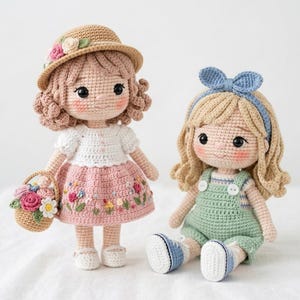 May include: Two handmade crochet dolls. One doll wears a straw hat with floral accents, a white top, and a pink skirt with embroidered flowers. The other doll wears a green romper with a blue bow headband and blue shoes.