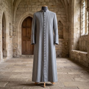May include: A floor-length, light gray cassock featuring a high mandarin collar, long sleeves with cuffs, and a full-length front button placket with numerous small, matching fabric-covered buttons extending from the neckline to the hem.