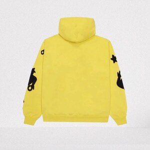May include: A bright yellow hoodie with a hood and long sleeves. The sleeves feature black graphic designs. The hoodie is made of a soft material and has a ribbed hem and cuffs. The background is a solid, neutral color.