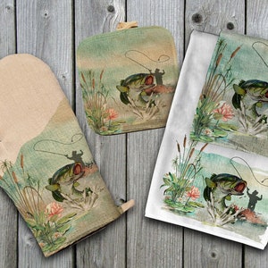May include: A set of three kitchen towels featuring a watercolor illustration of a bass fish jumping out of the water. The towels are white with a green, blue, and brown design. The towels are perfect for adding a touch of nature to your kitchen.