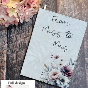 Puede incluir: Bolsa blanca con cremallera con un diseño floral y el texto "From Miss to Mrs." en letra cursiva negra.