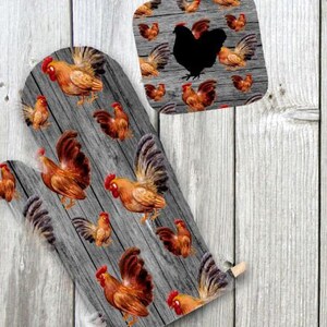 Puede incluir: Un guante de horno gris y marrón con un patrón de veta de madera y un diseño repetido de gallos. Los gallos son marrones, naranjas y rojos con ojos y picos negros.