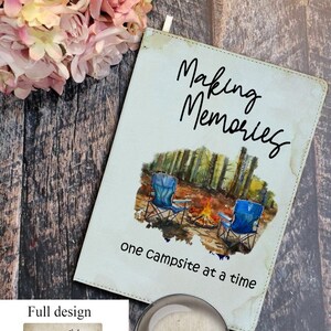 May include: A notebook with the words "Making Memories" in black script. The cover features a watercolor illustration of a campsite with two blue chairs and a campfire. The text "one campsite at a time" is below the illustration.