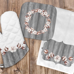 May include: Set of three kitchen accessories featuring a gray woodgrain design with white cotton flower accents. The set includes a pot holder, a trivet, and a tea towel.