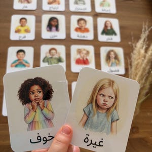 Peut inclure: Une collection de cartes éducatives rectangulaires présentant des illustrations à l'aquarelle d'enfants exprimant diverses émotions. Chaque carte affiche le visage et le buste d'un enfant avec du texte arabe imprimé en bas de carte.