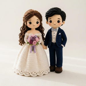 Può includere: Due bambole all'uncinetto che rappresentano una coppia di sposi. La figura a sinistra ha lunghi capelli castani e indossa un abito bianco con spalle scoperte e un bouquet di fiori viola e rosa. La figura a destra ha capelli neri e indossa un abito blu navy con camicia bianca, papillon grigio chiaro e scarpe marroni.