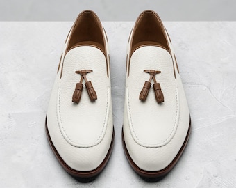 Mocassins masculinos de couro branco artesanal com borla e detalhes em marrom, modelo slip-on.
