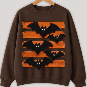 Halloween bat design in PNG format with black bats and orange patterned lines displayed on comfy t-shirt samples in charcoal, brown, olive green, rusty orange and cream for sublimation printing for the horror season and DTF t-shirts.