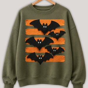 Halloween bat design in PNG format with black bats and orange patterned lines displayed on comfy t-shirt samples in charcoal, brown, olive green, rusty orange and cream for sublimation printing for the horror season and DTF t-shirts.