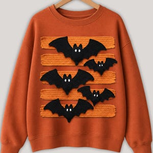 Halloween bat design in PNG format with black bats and orange patterned lines displayed on comfy t-shirt samples in charcoal, brown, olive green, rusty orange and cream for sublimation printing for the horror season and DTF t-shirts.