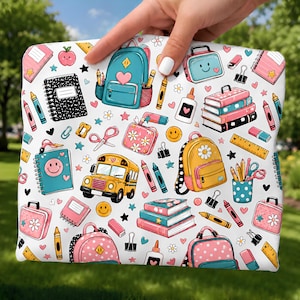 Könnte beinhalten: Ein weißer Beutel mit einem bunten Schulmotiv, das Illustrationen von gelben Schulbussen, Rucksäcken, Bücherstapeln, Notizbüchern, Klebeflaschen, Scheren, Linealen, Buntstiften, Radiergummis, Büroklammern und lächelnden Gesichtern zeigt.