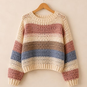 May include: A long-sleeve crochet sweater featuring horizontal stripes in cream, dusty rose, brown, and slate blue. The garment has a round neckline, ribbed cuffs, and a ribbed hem, constructed with an openwork stitch pattern throughout the body.