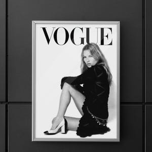 Puede incluir: Portada de la revista Vogue enmarcada en blanco y negro. La palabra "VOGUE" se muestra en letras may&uacute;sculas negras y grandes. La imagen muestra a una persona con un atuendo negro, sentada con una pierna doblada. La persona lleva tacones altos.