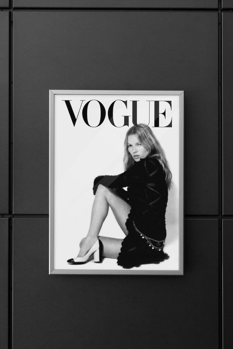 Puede incluir: Portada de la revista Vogue enmarcada en blanco y negro. La palabra "VOGUE" se muestra en letras may&uacute;sculas negras y grandes. La imagen muestra a una persona con un atuendo negro, sentada con una pierna doblada. La persona lleva tacones altos.