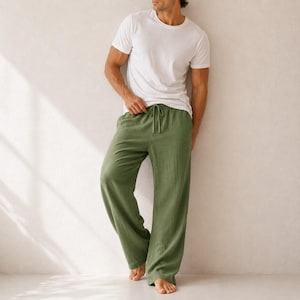 May include: A plain white short-sleeved crew neck t-shirt paired with loose-fitting olive green trousers. The trousers feature a wide-leg silhouette, a comfortable elasticated waistband, and a matching drawstring tie at the center front.