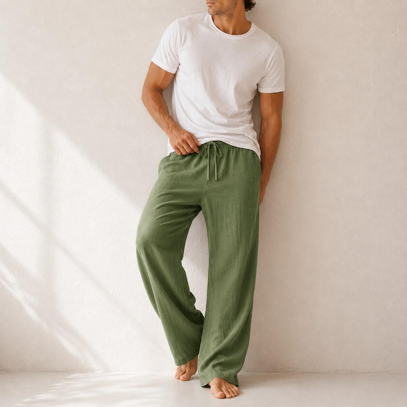 May include: A plain white short-sleeved crew neck t-shirt paired with loose-fitting olive green trousers. The trousers feature a wide-leg silhouette, a comfortable elasticated waistband, and a matching drawstring tie at the center front.