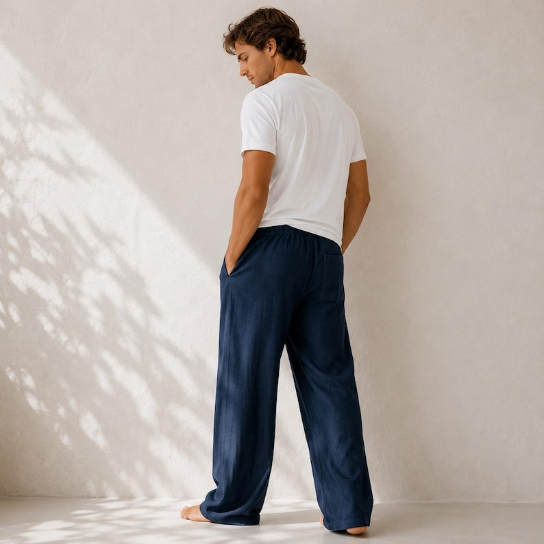 May include: A plain white short-sleeved t-shirt paired with loose-fitting navy blue trousers. The trousers feature a straight-leg cut, a visible back pocket on the right side, and a relaxed silhouette that falls straight to the floor.