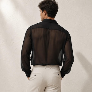 May include: A long-sleeved black shirt made of a sheer, translucent fabric with a classic collar and buttoned cuffs, paired with light beige trousers featuring a structured waistband, belt loops, and visible back pockets with button closures.