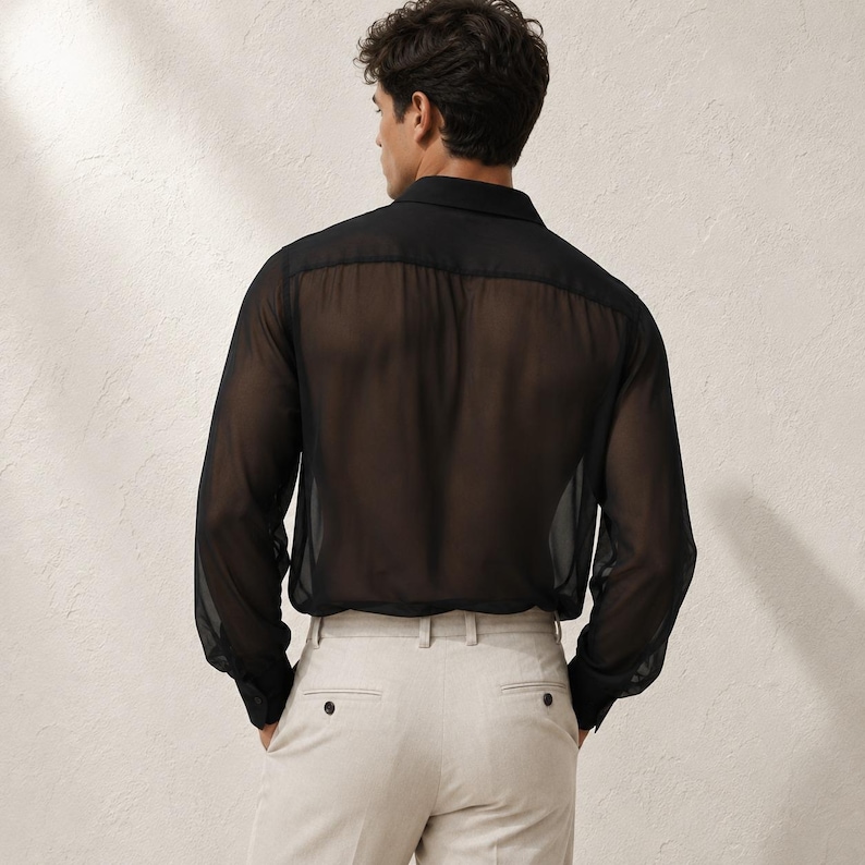 May include: A long-sleeved black shirt made of a sheer, translucent fabric with a classic collar and buttoned cuffs, paired with light beige trousers featuring a structured waistband, belt loops, and visible back pockets with button closures.