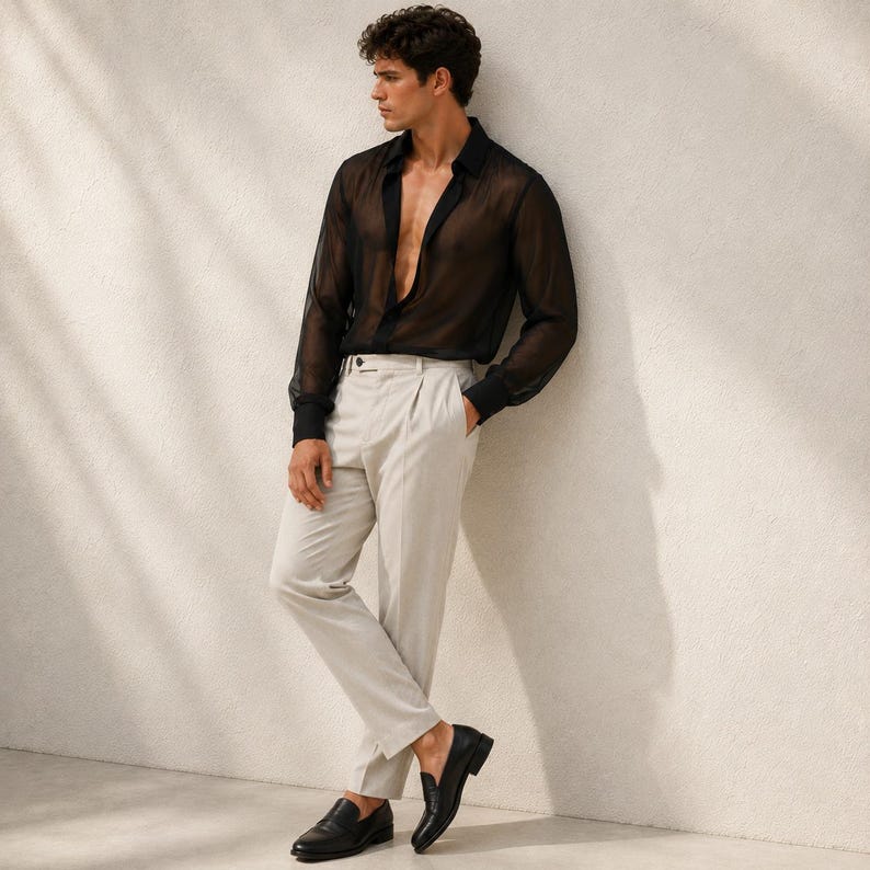 May include: A sheer black long-sleeved button-down shirt with a classic collar, paired with light beige pleated trousers featuring a straight-leg cut and a clean waistband, complemented by polished black leather loafers with a low heel.
