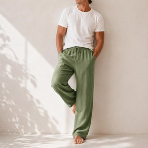 May include: A plain white short-sleeved crew neck t-shirt paired with loose-fitting olive green trousers. The trousers feature a drawstring waist with matching green ties and a straight-leg cut, providing a relaxed and comfortable fit for daily wear.