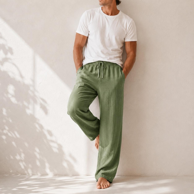 May include: A plain white short-sleeved crew neck t-shirt paired with loose-fitting olive green trousers. The trousers feature a drawstring waist with matching green ties and a straight-leg cut, providing a relaxed and comfortable fit for daily wear.