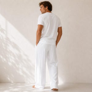 May include: A solid white short-sleeved t-shirt paired with matching white long trousers. The outfit features a clean, plain design with a standard crew neckline and a relaxed fit, showcasing a simple and uniform monochromatic white color scheme.