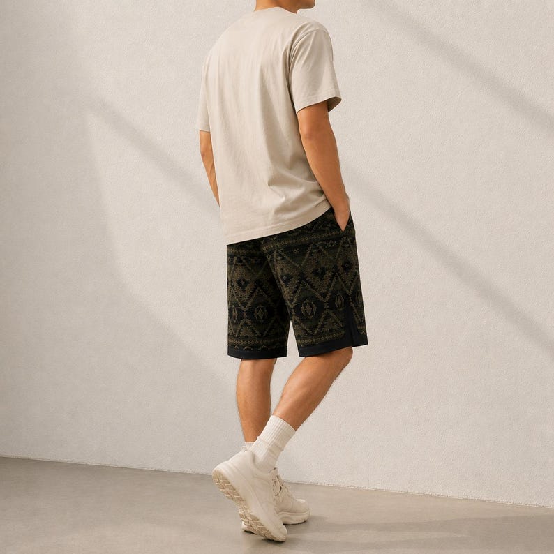 May include: A beige short-sleeved t-shirt paired with dark green shorts featuring a black geometric pattern. The shorts have a straight-leg cut and a solid black hem detail. The outfit is completed with white crew socks and white athletic sneakers.