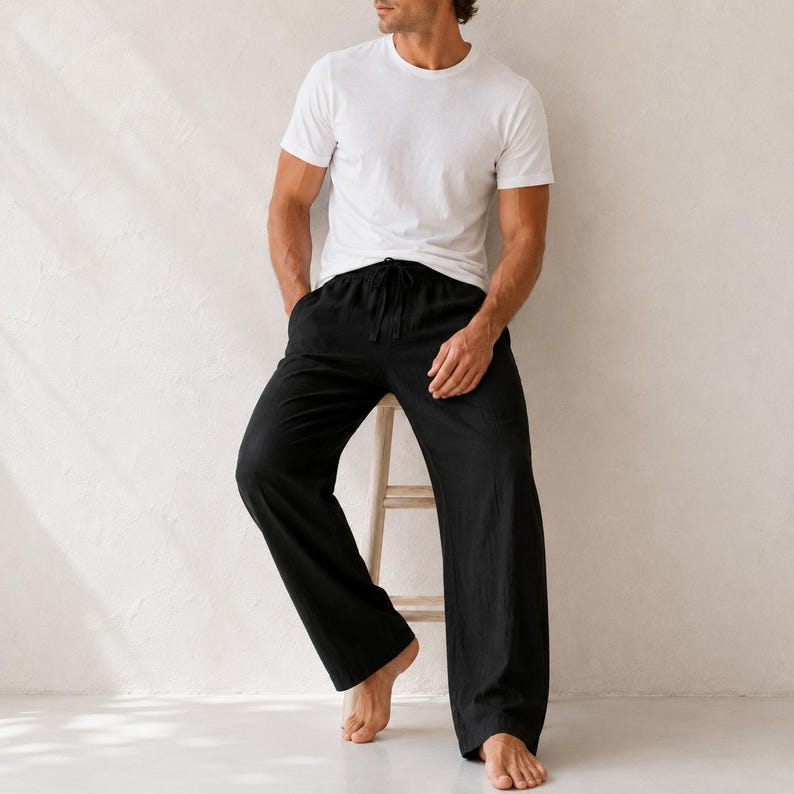 May include: A plain white short-sleeved crew neck t-shirt paired with loose-fitting black trousers. The trousers feature a drawstring waist with a visible tie closure and a wide-leg silhouette, providing a relaxed and comfortable fit for daily wear.