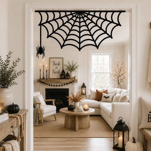 Puede incluir: Una decoración de esquina en forma de telaraña negra con una araña colgante, diseñada para montarse en el marco de una puerta. La pieza recortada presenta un patrón simétrico con líneas radiantes y arcos concéntricos de material plano.