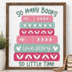 May include: A square wall sign with a dark wood frame and white shiplap background featuring a stack of five colorful books. The text reads SO MANY BOOKS at the top and SO LITTLE TIME at the bottom, with love story written on a teal book spine.