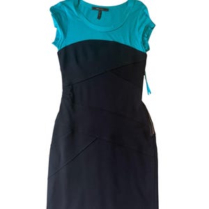 May include: A sleeveless dress with a turquoise top and a black skirt. The top has a scoop neck and short sleeves. The black skirt has diagonal seams. The dress is a sheath style and appears to be made of a stretchy material.