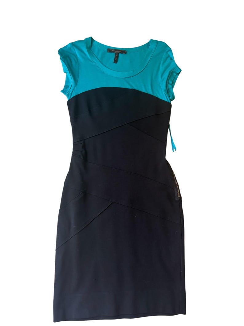 May include: A sleeveless dress with a turquoise top and a black skirt. The top has a scoop neck and short sleeves. The black skirt has diagonal seams. The dress is a sheath style and appears to be made of a stretchy material.