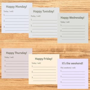 May include: Six pastel-coloured sticky notes arranged on a wooden surface, each labelled with a day of the week. The notes feature the phrases "Happy Monday!" to "It's the weekend!" and provide space for a to-do list.