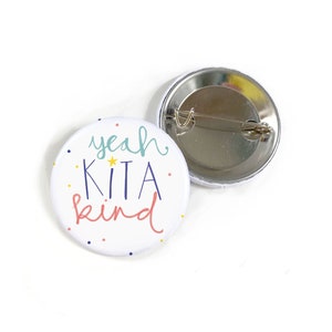 Può includere: Un bottone bianco con un design colorato che dice "yeah kita kind" con una stella gialla. Il retro del bottone è argentato con uno spillo.