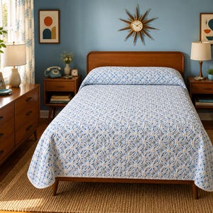 May include: A bedroom with a wooden bed covered in a blue and white patterned quilt. The room has a mid-century modern style, with wooden furniture, including a dresser and bedside tables. A starburst clock hangs on the wall. The color scheme is blue and brown.