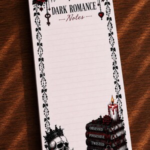 Op de afbeelding: Een notitieblok met gothic-thema en lijnen. De bovenkant toont "DARK ROMANCE - Notes" met bloemen- en sleutelaccenten. Een schedel met kroon en rozen, en een stapel boeken met de woorden "Obsessed, Possessive, Twisted, Yours" zijn afgebeeld.